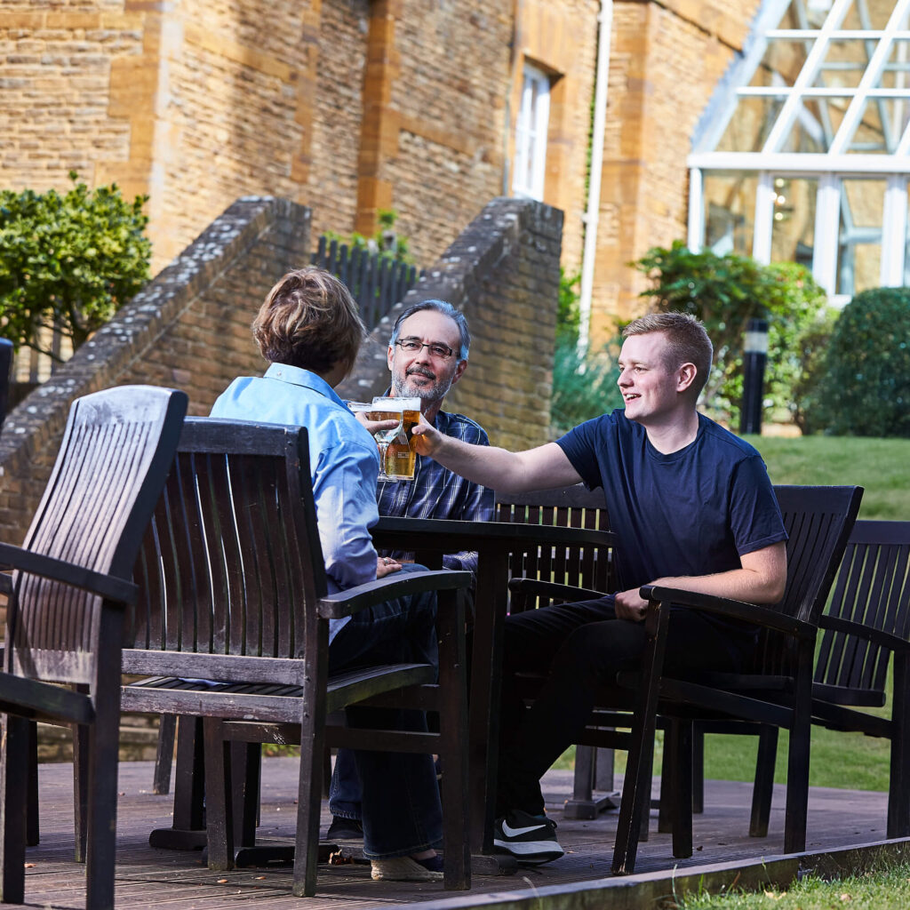 A son cheersing with his parents in a beer garden
